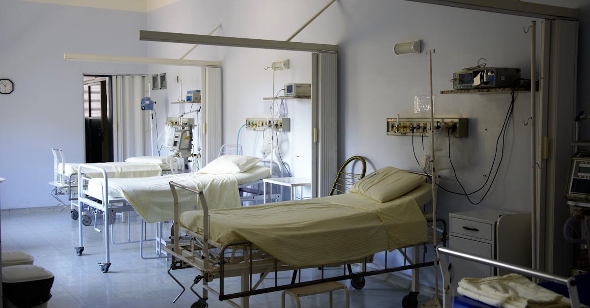 Spacious hospital room with several empty beds and medical equipment, emphasizing healthcare and hygiene.